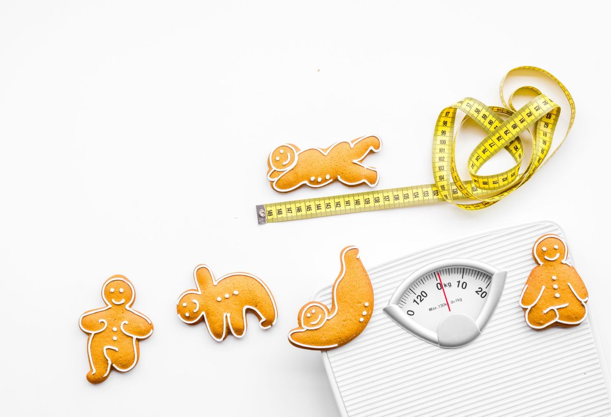 Ways for lose weight. Sport. Cookies in shape of yoga asans near scale and measuring tape on white background top view copy space